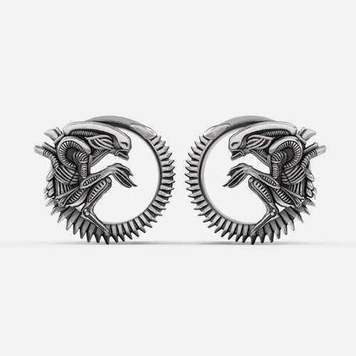 Pair of silver-tone alien invasion tunnels with ridged spine detail and coiled creature motif, front view