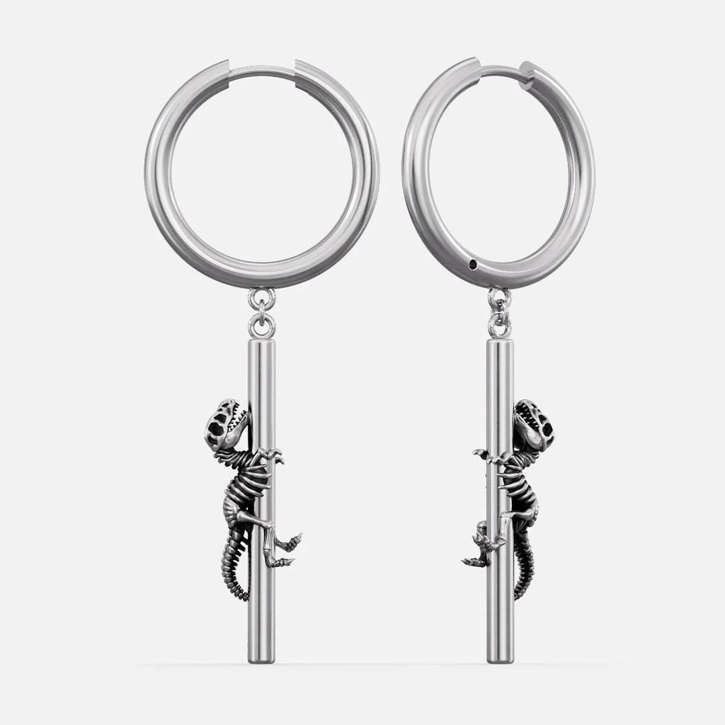 Silver-tone hoop earrings with a dangling dinosaur skeleton charm climbing a bar, shown as a pair