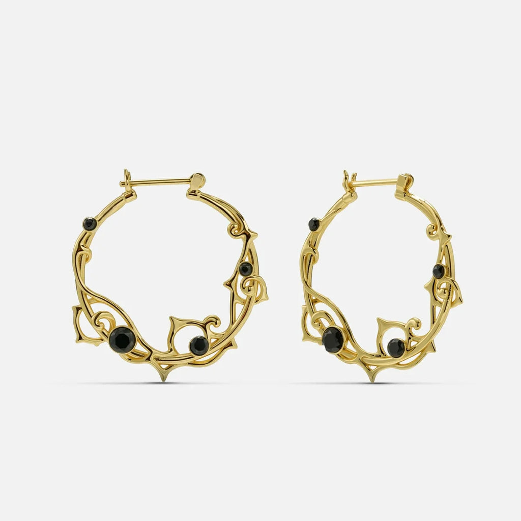 Pair of gold-tone vine hoop earrings with black stone accents on a plain background