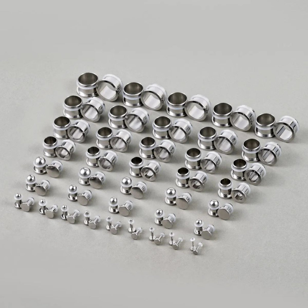 Full set of steel ear stretching plugs and tunnels arranged in graduated sizes on a flat surface