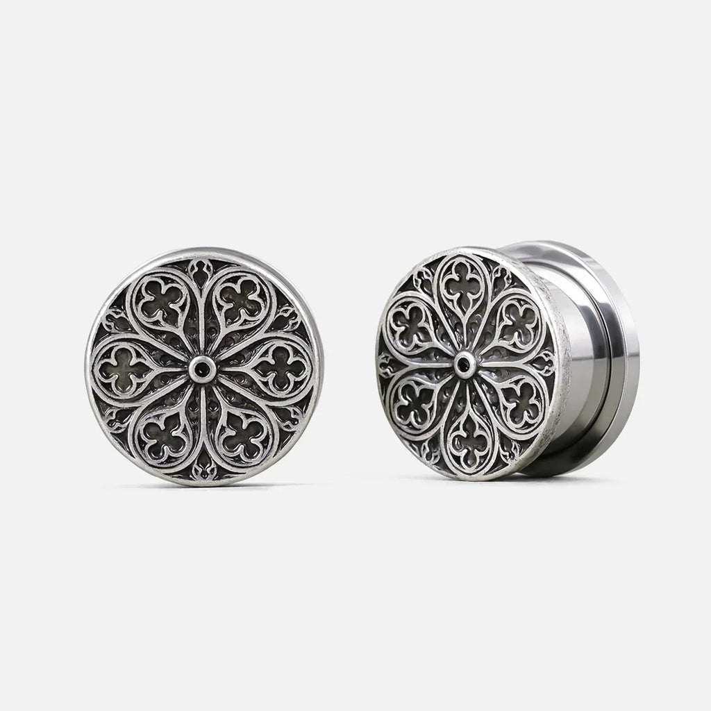 Pair of silver-tone ear plugs with a round cathedral rose window design, front and side view