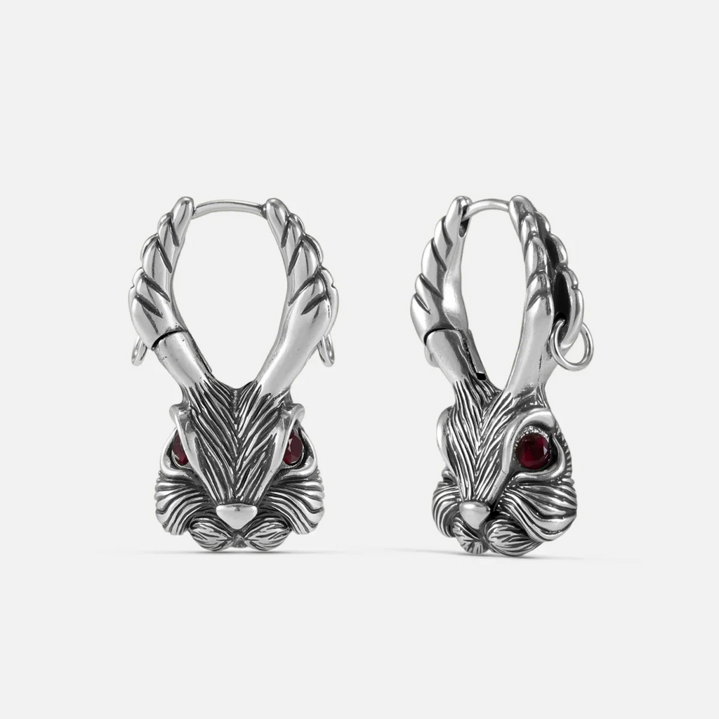 Pair of oxidized silver-tone jackalope hoop earrings with antlers and red gemstone eyes, front view