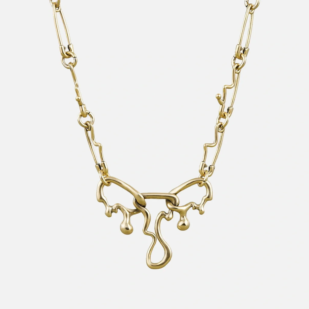 Gold-tone fluid pin necklace with a wavy paperclip chain and dripping abstract pendant, front view