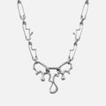Silver-tone fluid pin necklace with a wavy paperclip chain and dripping abstract pendant, front view