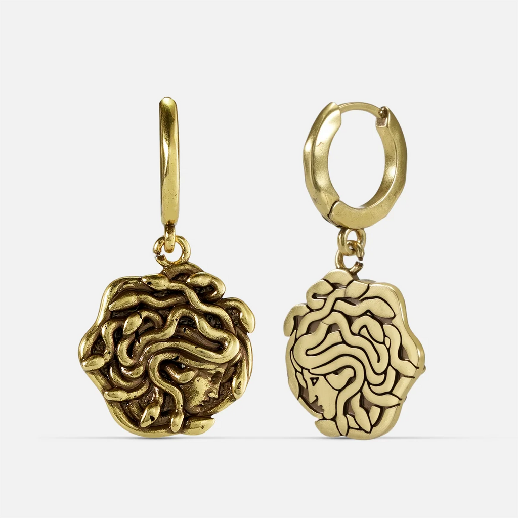 petrifying gaze dangle earrings in gold shown in a front and back view, featuring medusa-inspired drop charms suspended from small hoops